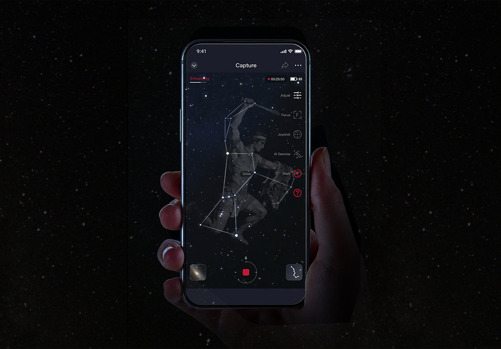 Hand holding a smartphone with a stargazing app on a dark background